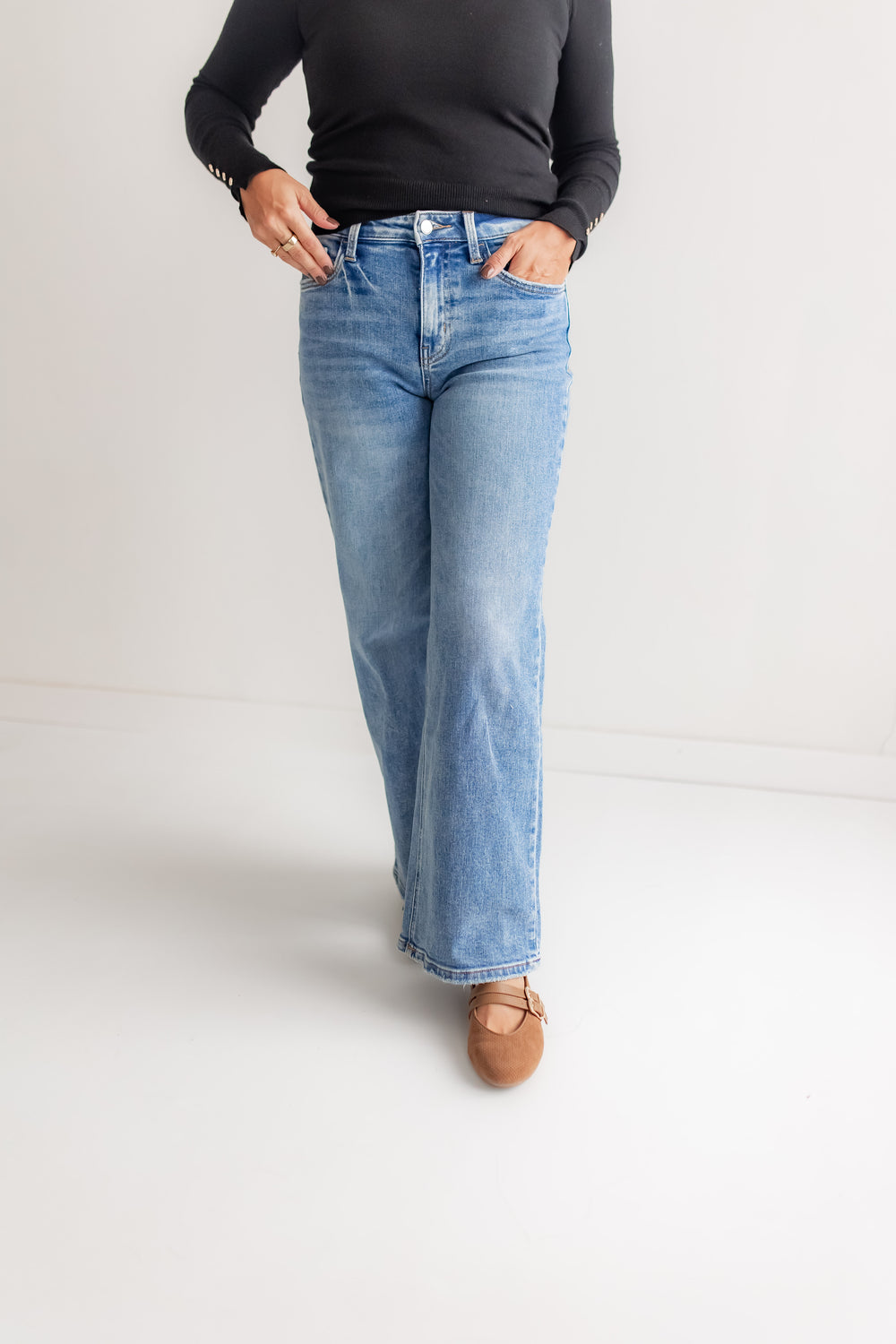 A woman wears high-rise, light-wash, wide-leg denim jeans.