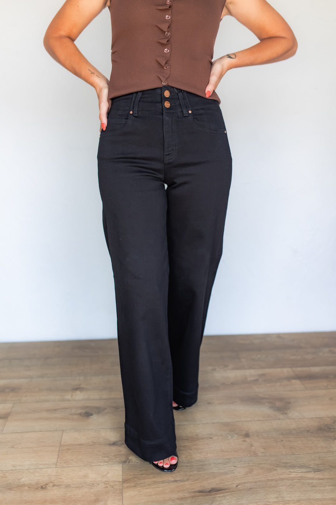 Close-up of black wide leg jeans with double button waistband detail