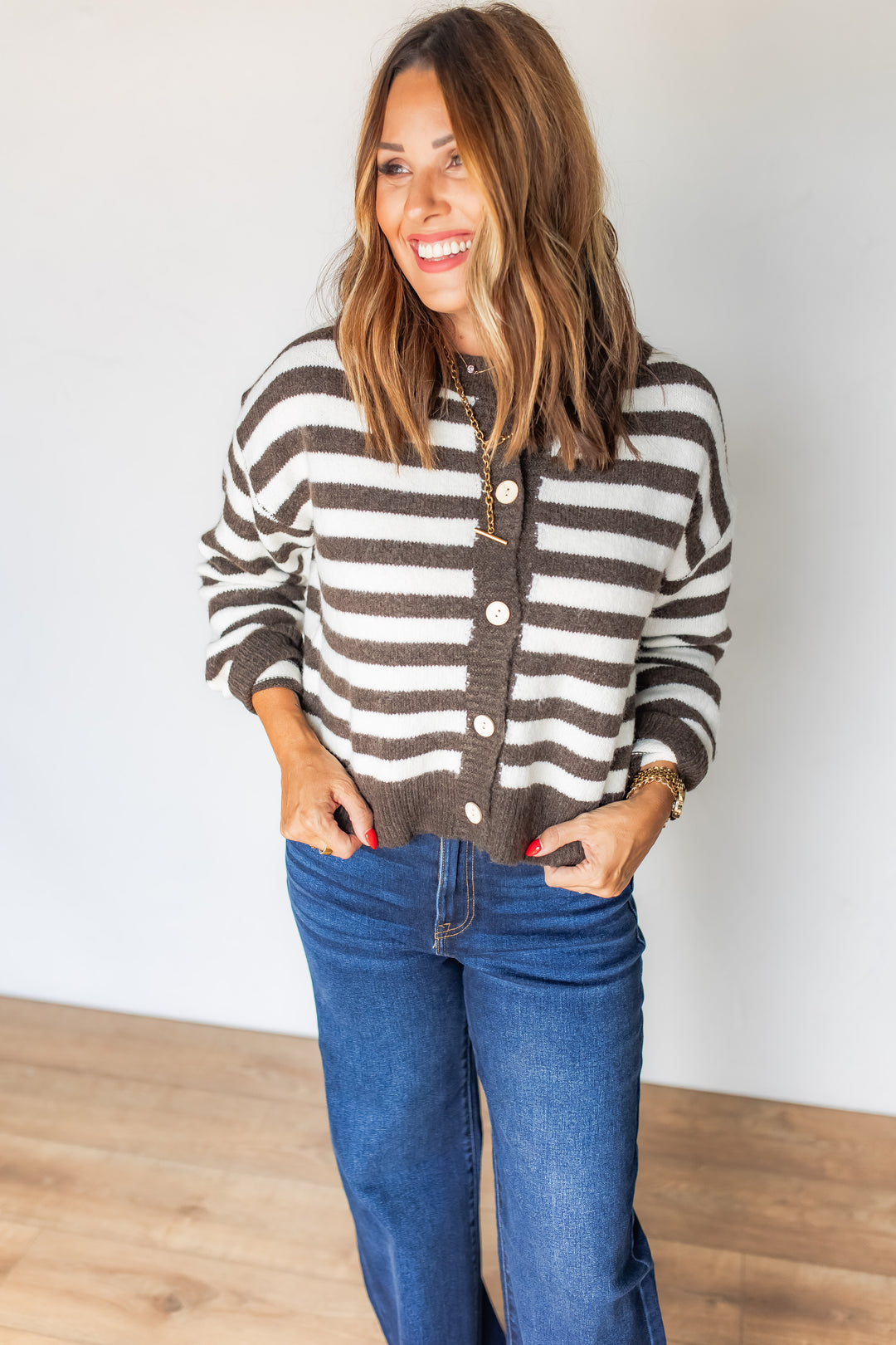 Woman wearing brown and cream striped cardigan with dark wash jeans