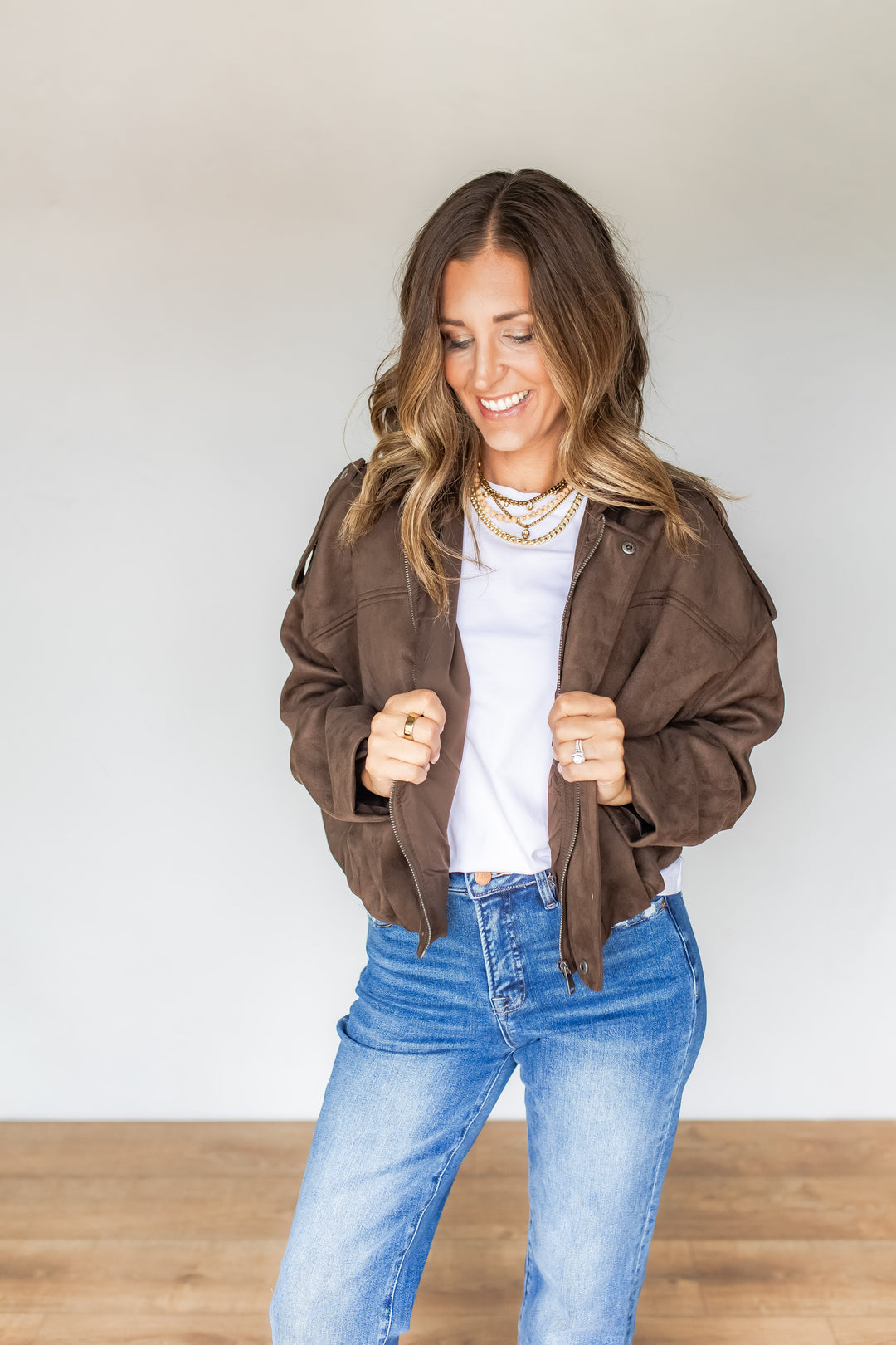 Woman wearing oversized brown suede jacket over white tee and jeans