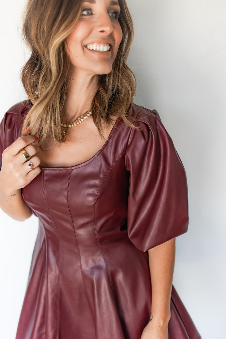 Close-up of burgundy faux leather dress front neck and seaming detail
