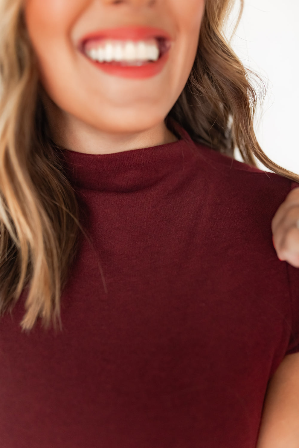 Close-up of burgundy mock neckline detail on fitted top