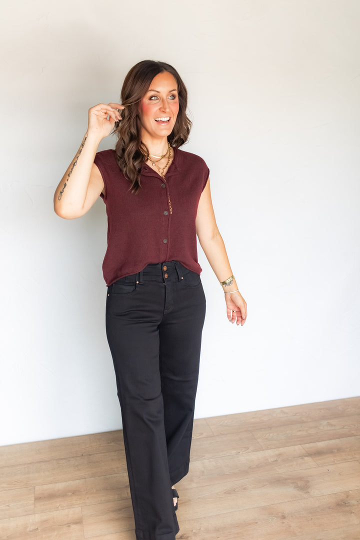 Woman wearing burgundy sweater knit button top with black jeans