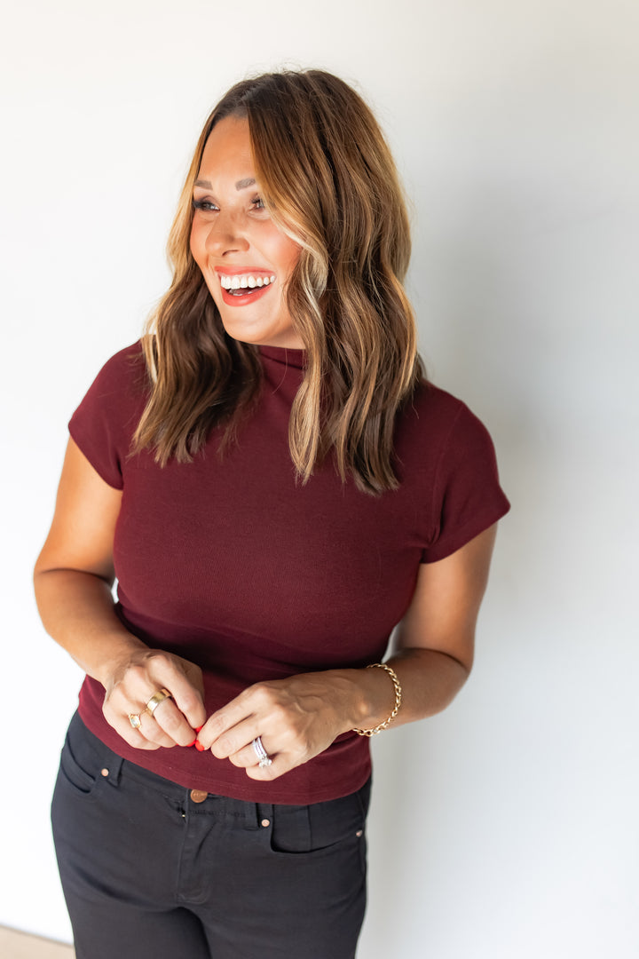 Close-up of burgundy mock neck top styled with black jeans