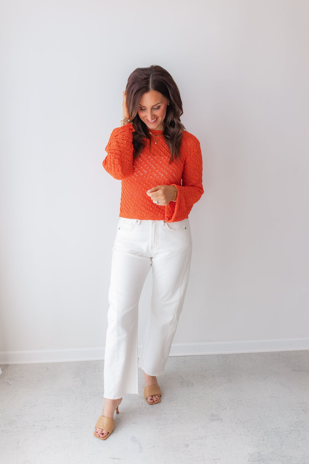 Bright coral spring sweater outfit styled with white denim jeans and heels.