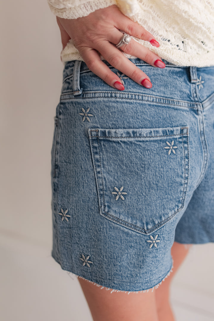 Close up of daisy embroidery detail on high rise denim shorts