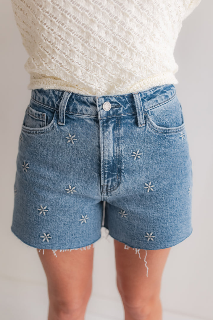 Woman wearing embroidered floral denim shorts styled with a lightweight sweater for a spring outfit