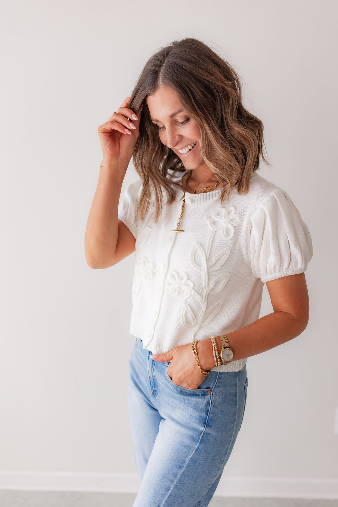 A white floral embroidered puff sleeve knit top styled with denim