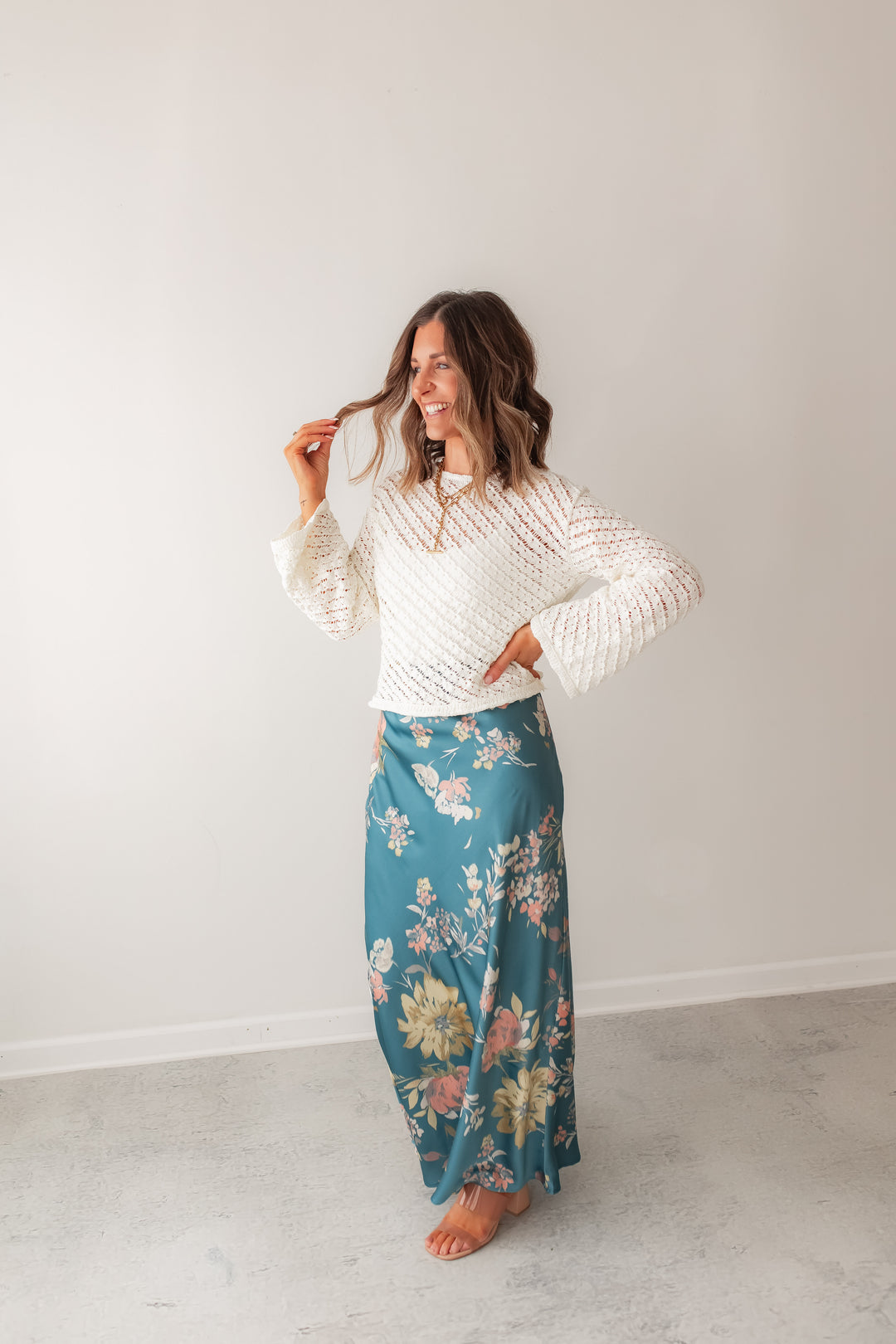 A teal floral satin maxi skirt styled with white knit sweater