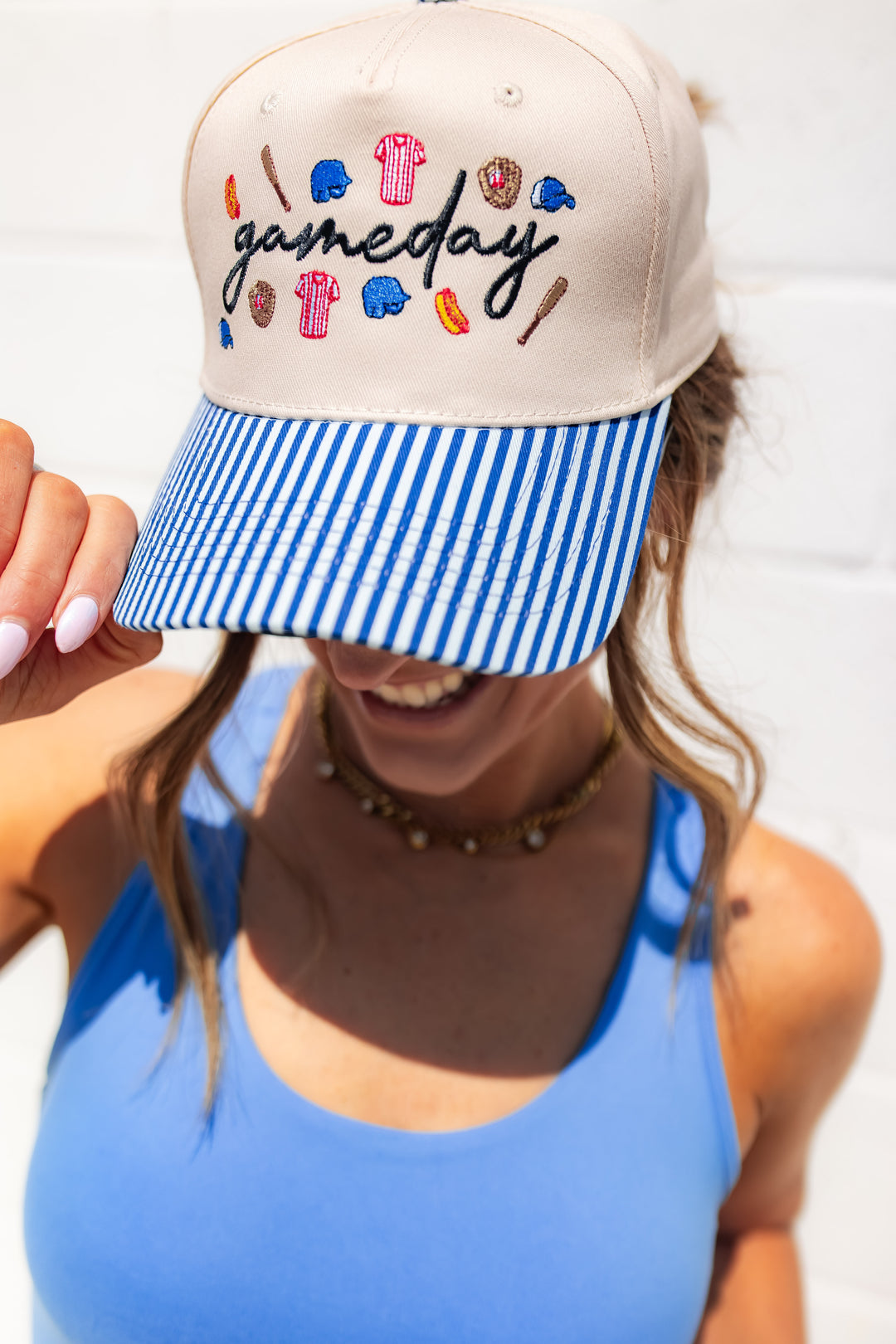 Gameday baseball hat with blue striped bill and embroidered sports icons for casual game day outfits