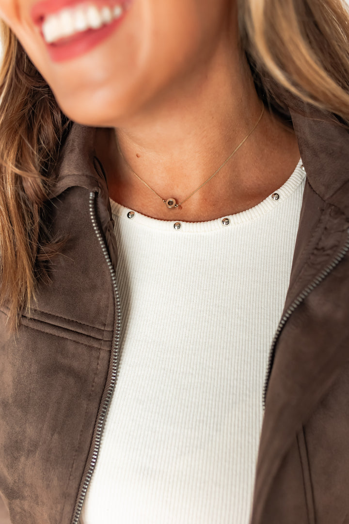 Close-up of silver stud detail along neckline of ivory tank top