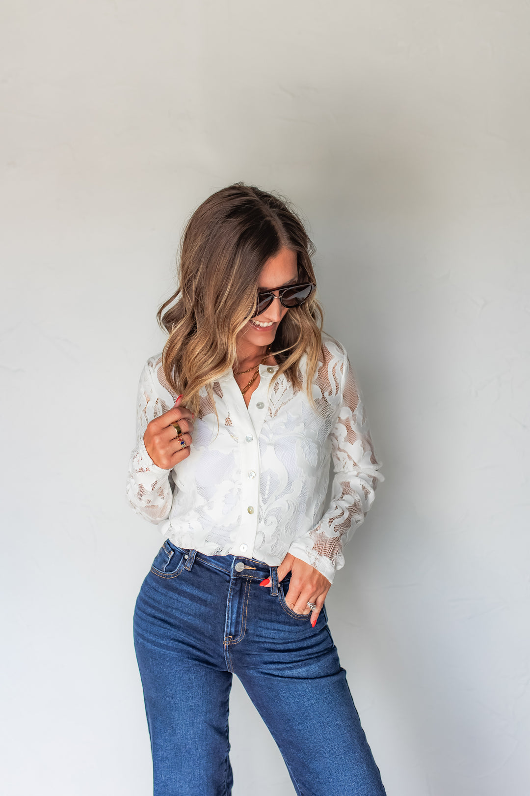 Woman wearing white lace button-up top with wide leg jeans