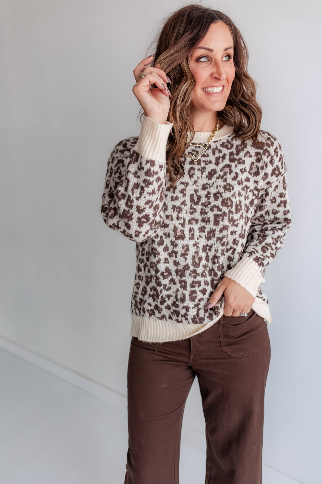 Woman wearing a cozy leopard sweater with brown pants. 