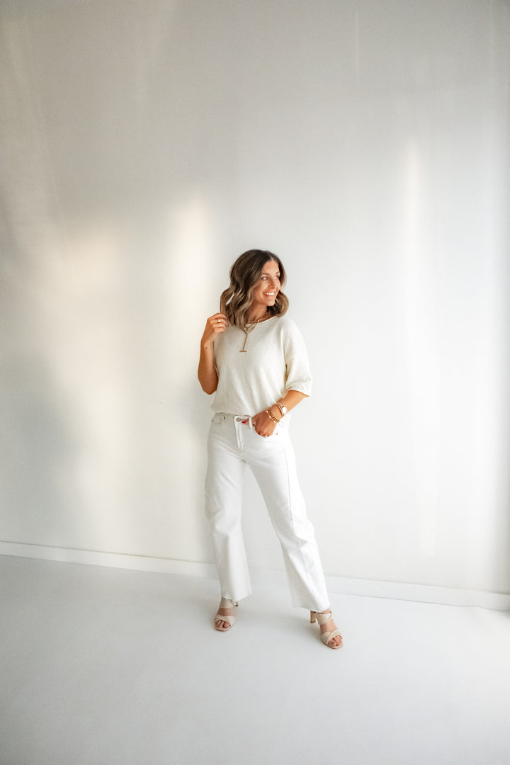 Lightweight ivory knit top for women worn with white denim pants. 