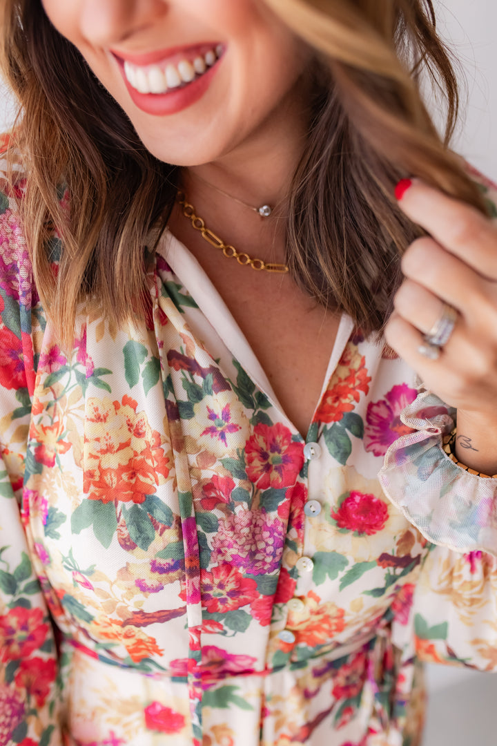 Close up of lightweight floral romper with tassel tie detail and buttons