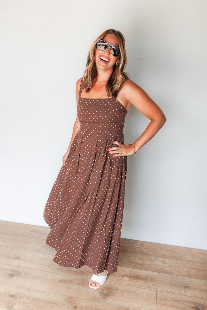 Woman wearing brown polka dot midi dress with white sandals