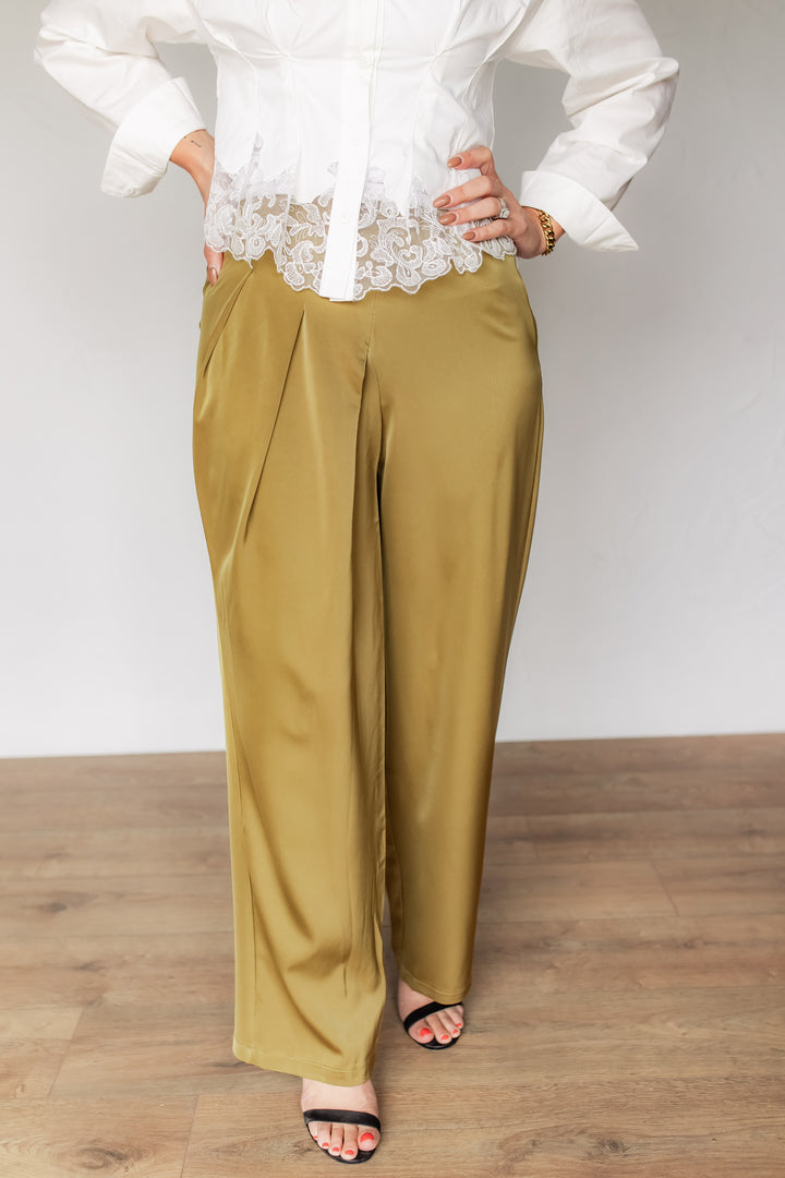Woman wearing olive gold satin wide leg pants with a white lace-trim blouse