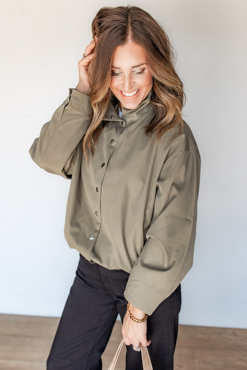 Close-up of olive jacket funnel neck collar and silver snap button detail