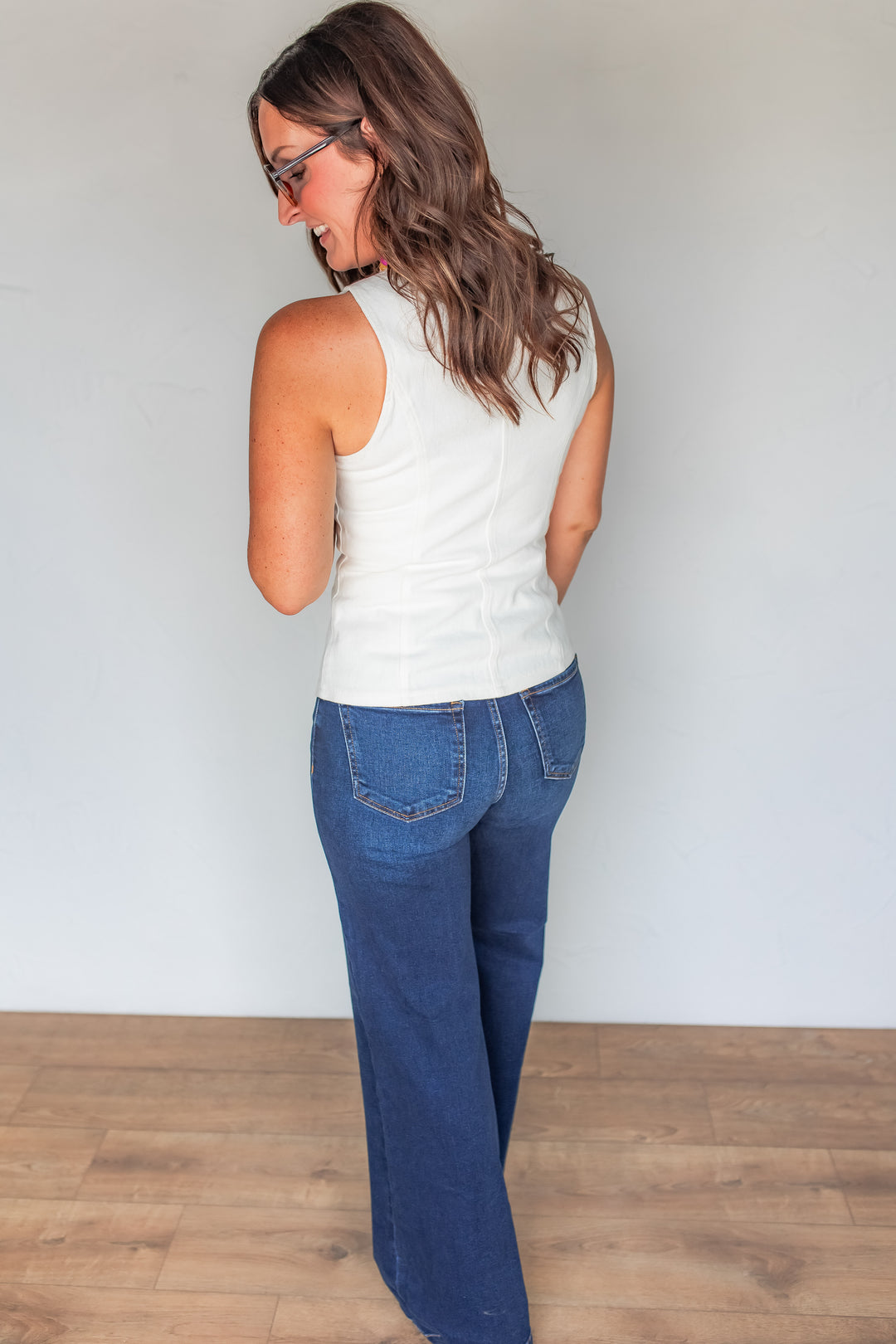 Back view of white denim vest showing fitted silhouette