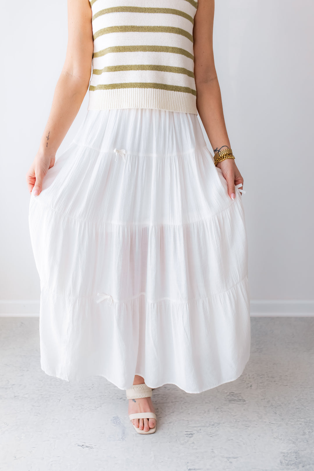 Woman wearing a white tiered maxi skirt with small bows styled for spring and summer