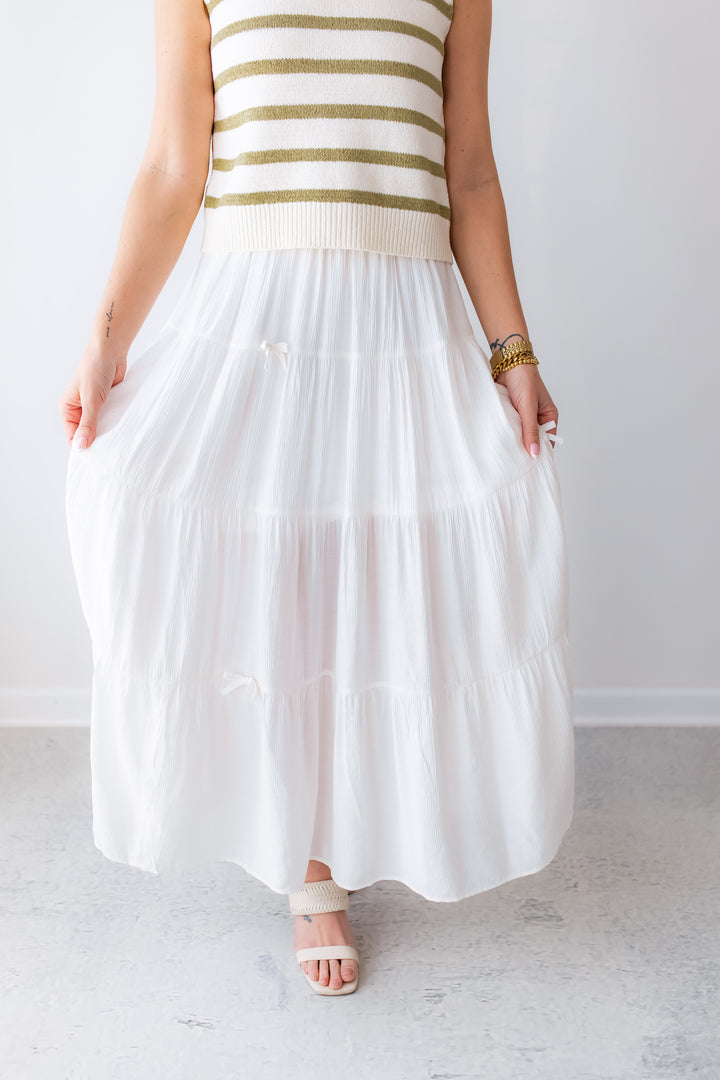 Woman wearing a white tiered maxi skirt with small bows styled for spring and summer